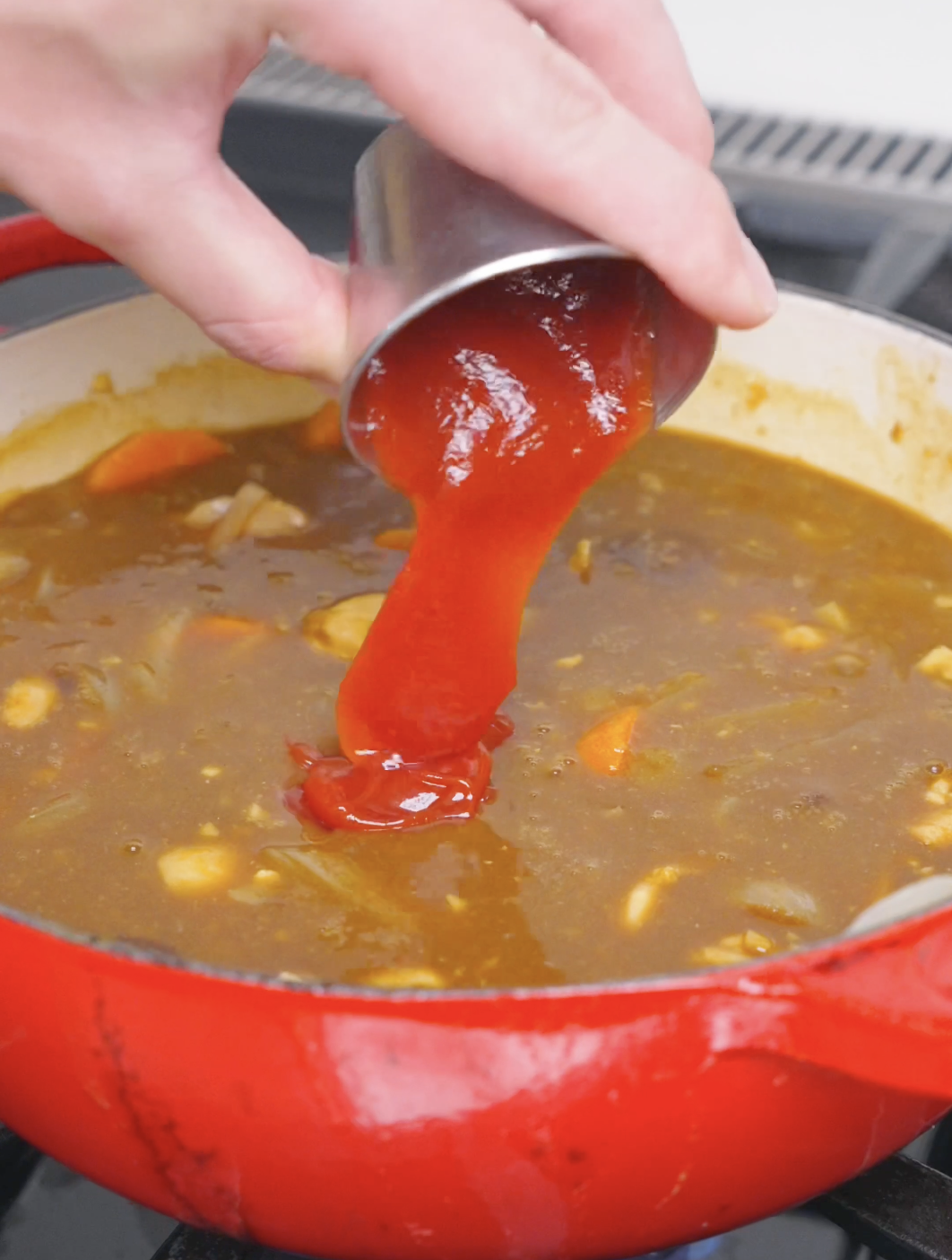 Ketchup being poured into the thickened curry to season it for Chicken Curry Stew Recipe.