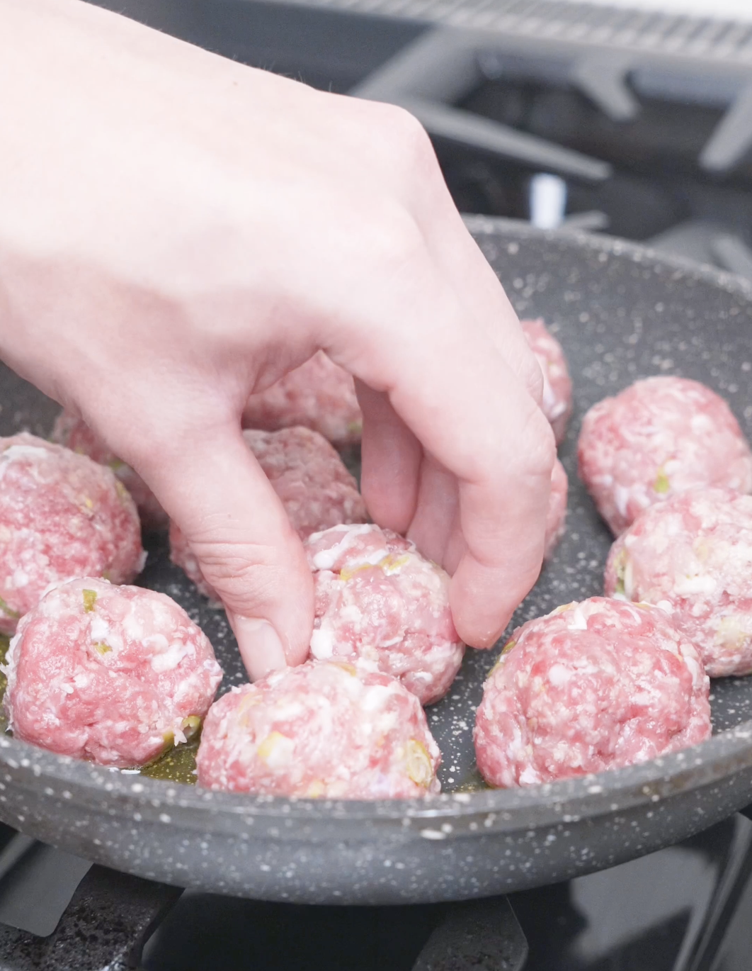 Raw meatballs being arranged in a single layer in an oiled pan for Teriyaki Meatballs Recipe.