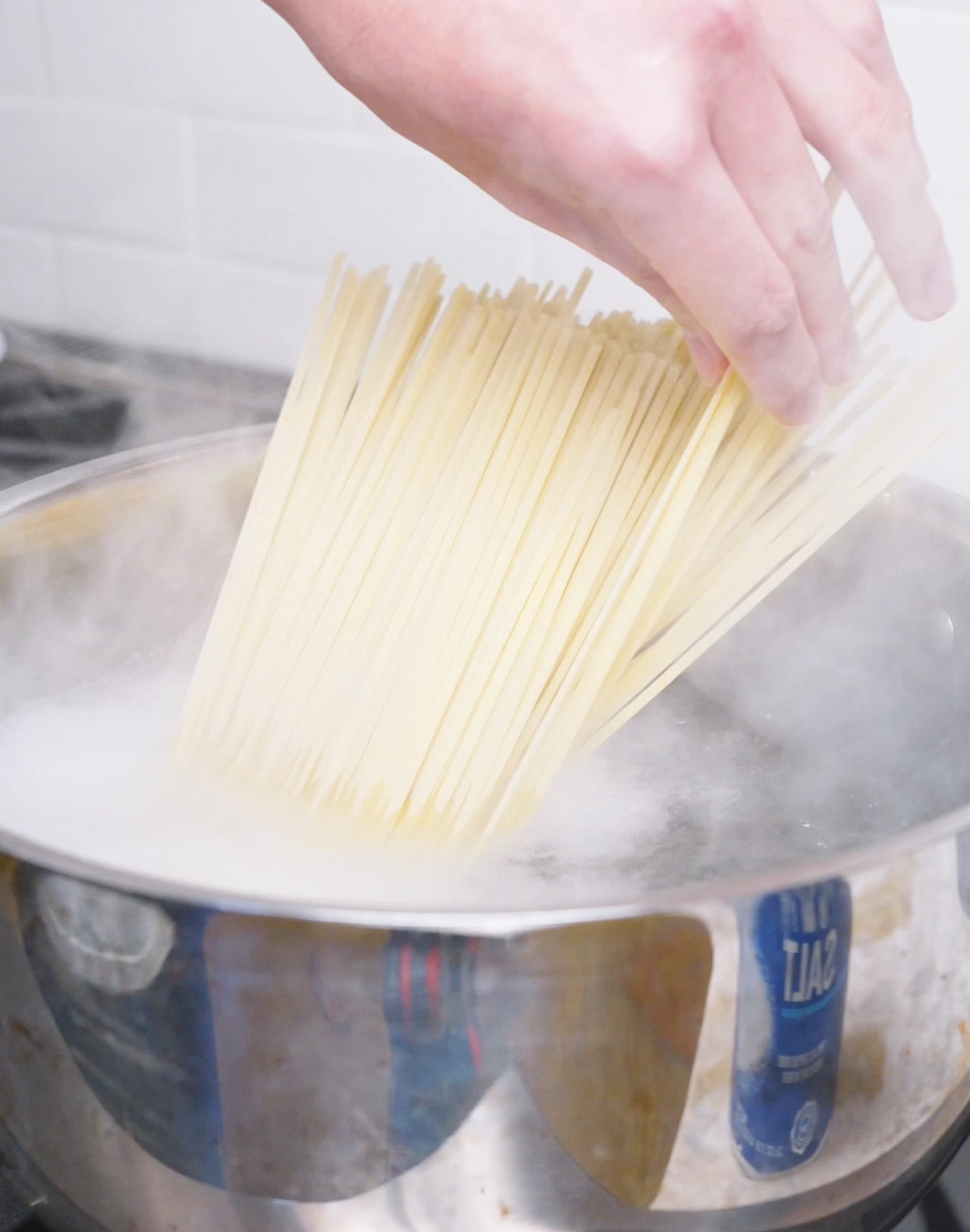 A bundle of dried noodles being lowered into boiling water for Kung Pao Chicken Noodles Recipe.