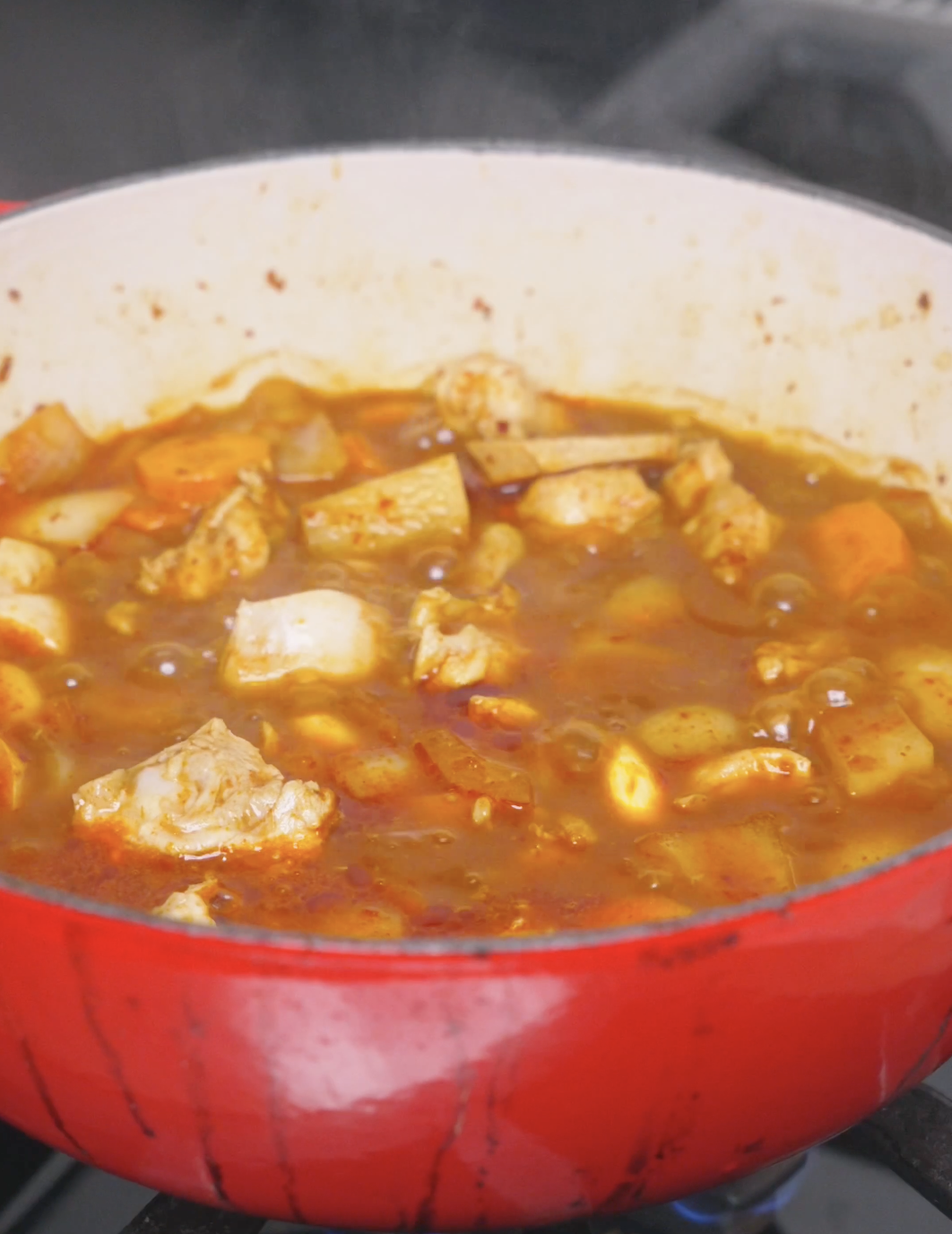 Chicken, potatoes, and carrots bubbling away in the spicy broth until tender for Korean Braised Chicken Recipe.