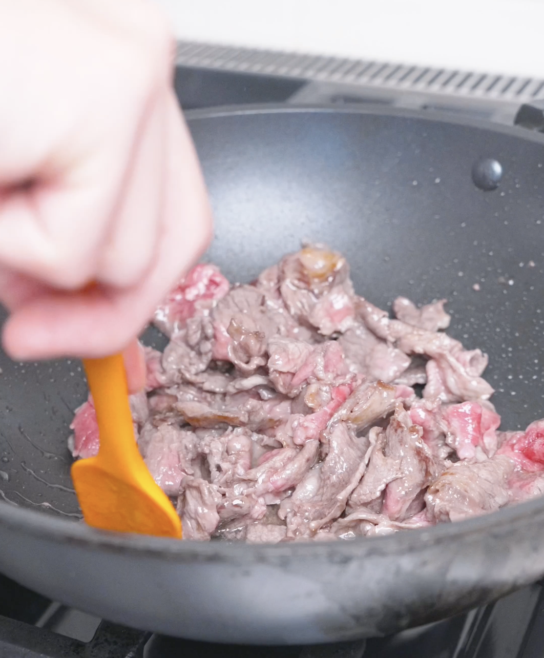 Thinly sliced beef being stirred in a wok until nearly cooked through for Curry Fried Rice Recipe.