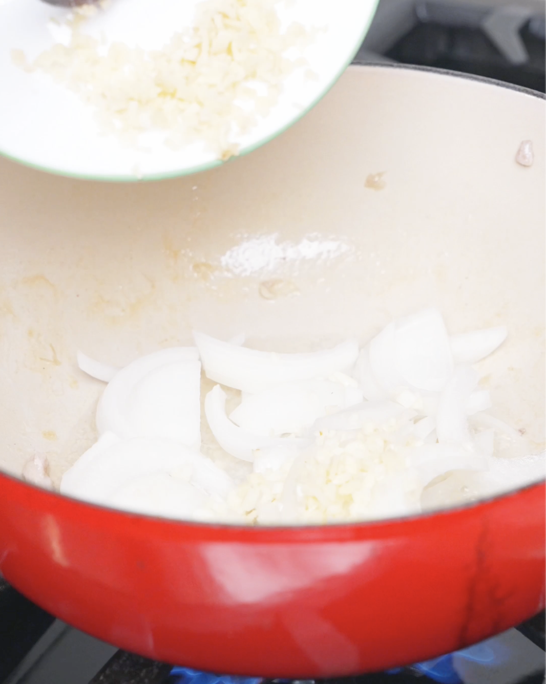 Minced garlic and ginger being added to thinly sliced onions in the pot for Chicken Curry Stew Recipe.