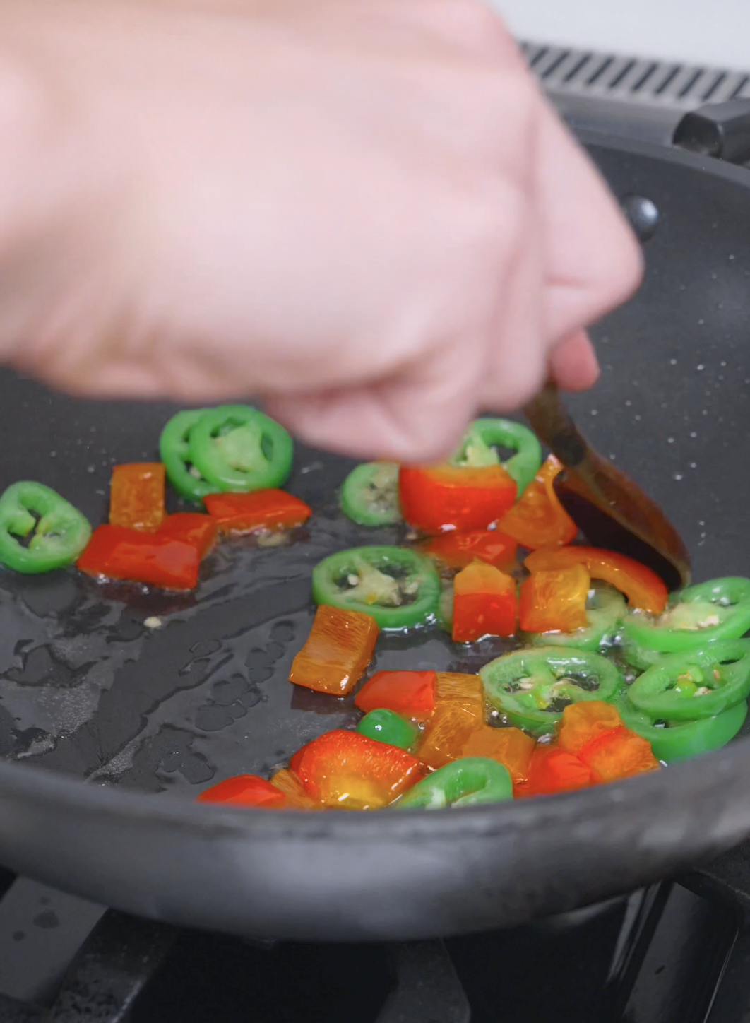 Red bell pepper chunks and jalape&ntilde;o rings softening in a pan for Salt and Pepper Shrimp Recipe.