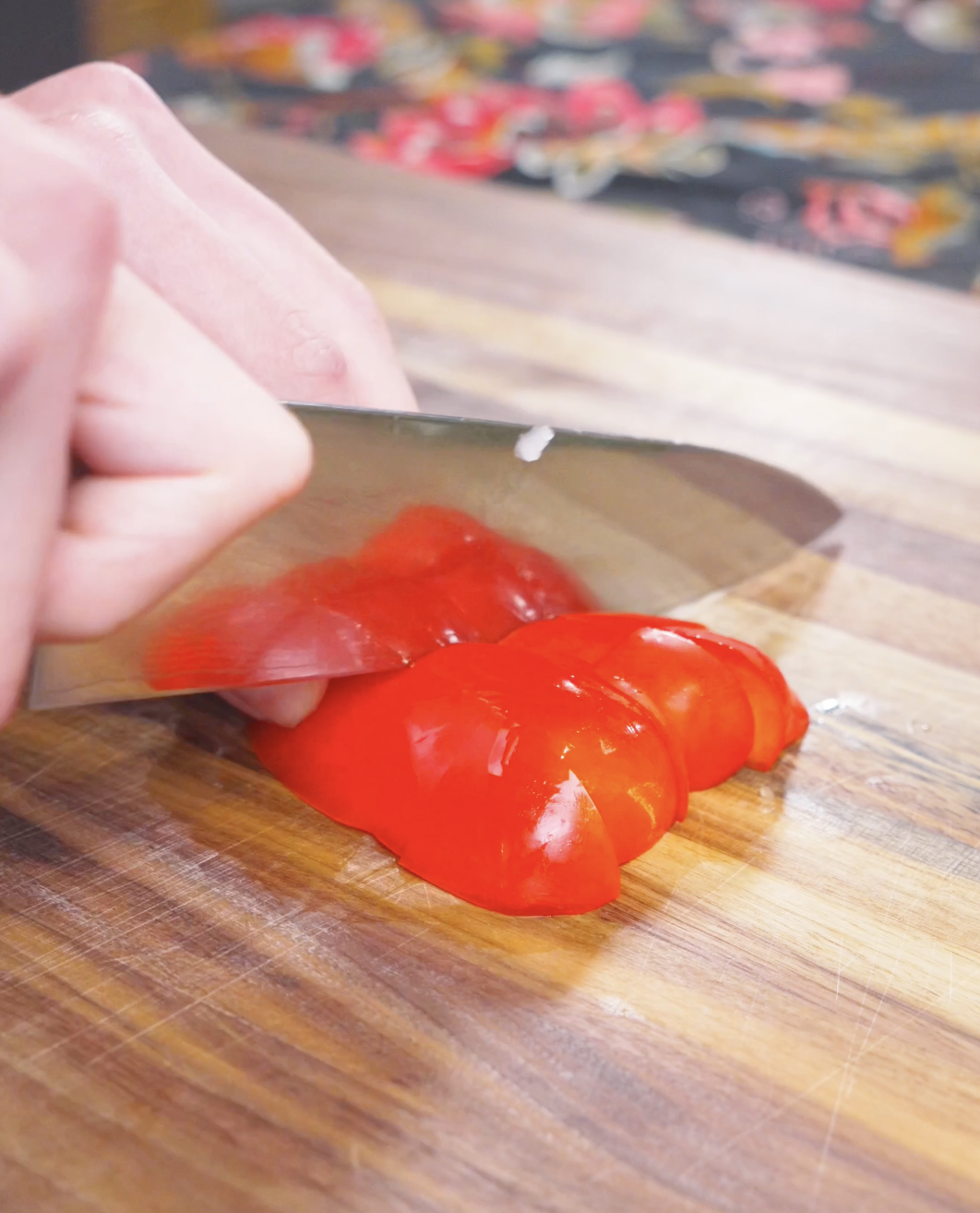 Red bell pepper being cut into big bite-sized chunks on a wooden board for Kung Pao Chicken Noodles Recipe.