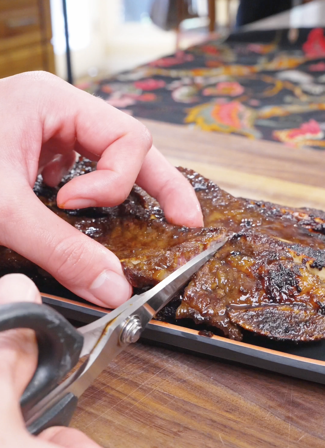 Kitchen shears cutting the grilled short ribs into pieces on a platter for Korean BBQ Short Rib Recipe.
