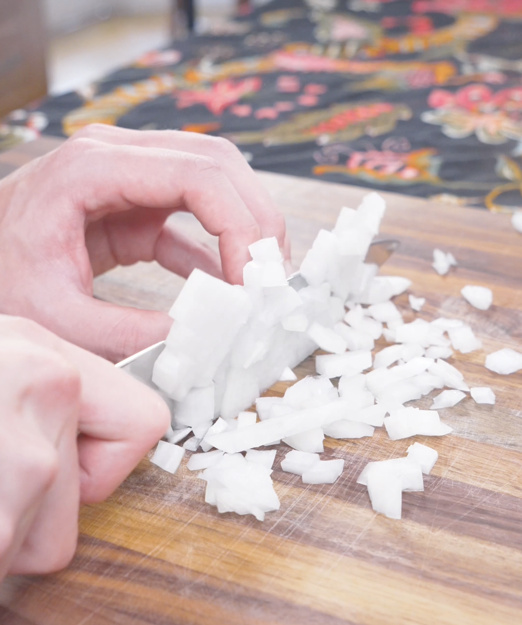 Onion being finely diced on a wooden cutting board while prepping Curry Fried Rice Recipe.