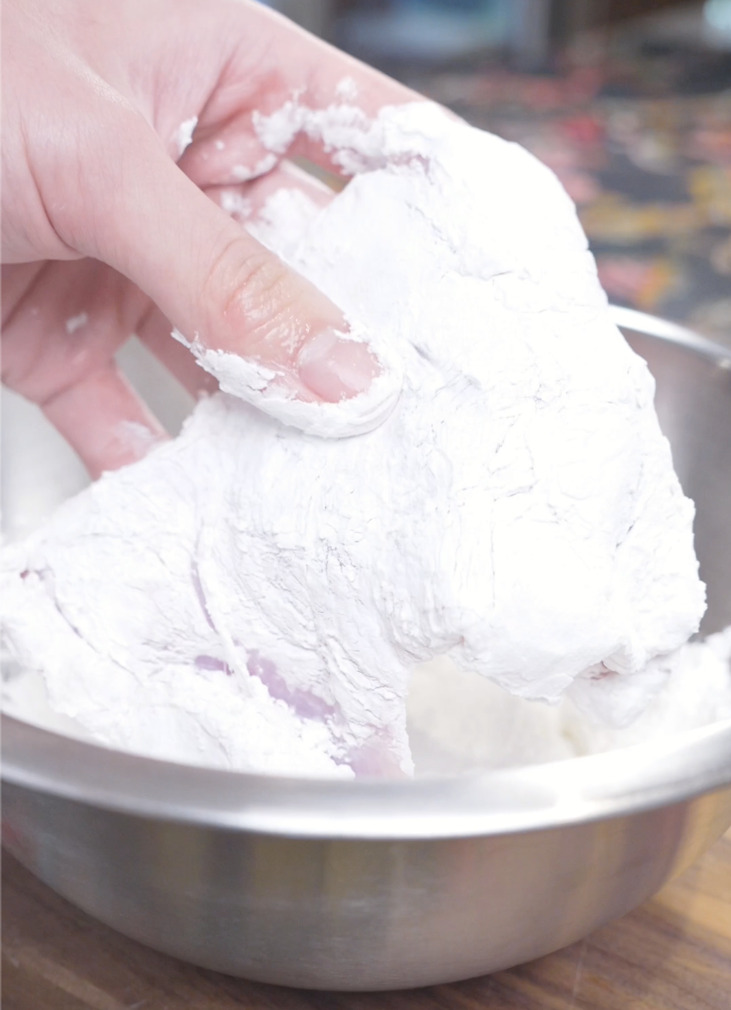 Chicken thighs being pressed into seasoned cornstarch until fully coated for Creamy Gochujang Chicken Recipe.