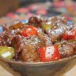 Finished Black Pepper Steak Bites Recipe in a ceramic bowl with red and green peppers and cracked black pepper.