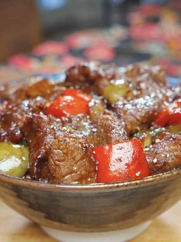 Finished Black Pepper Steak Bites Recipe in a ceramic bowl with red and green peppers and cracked black pepper.