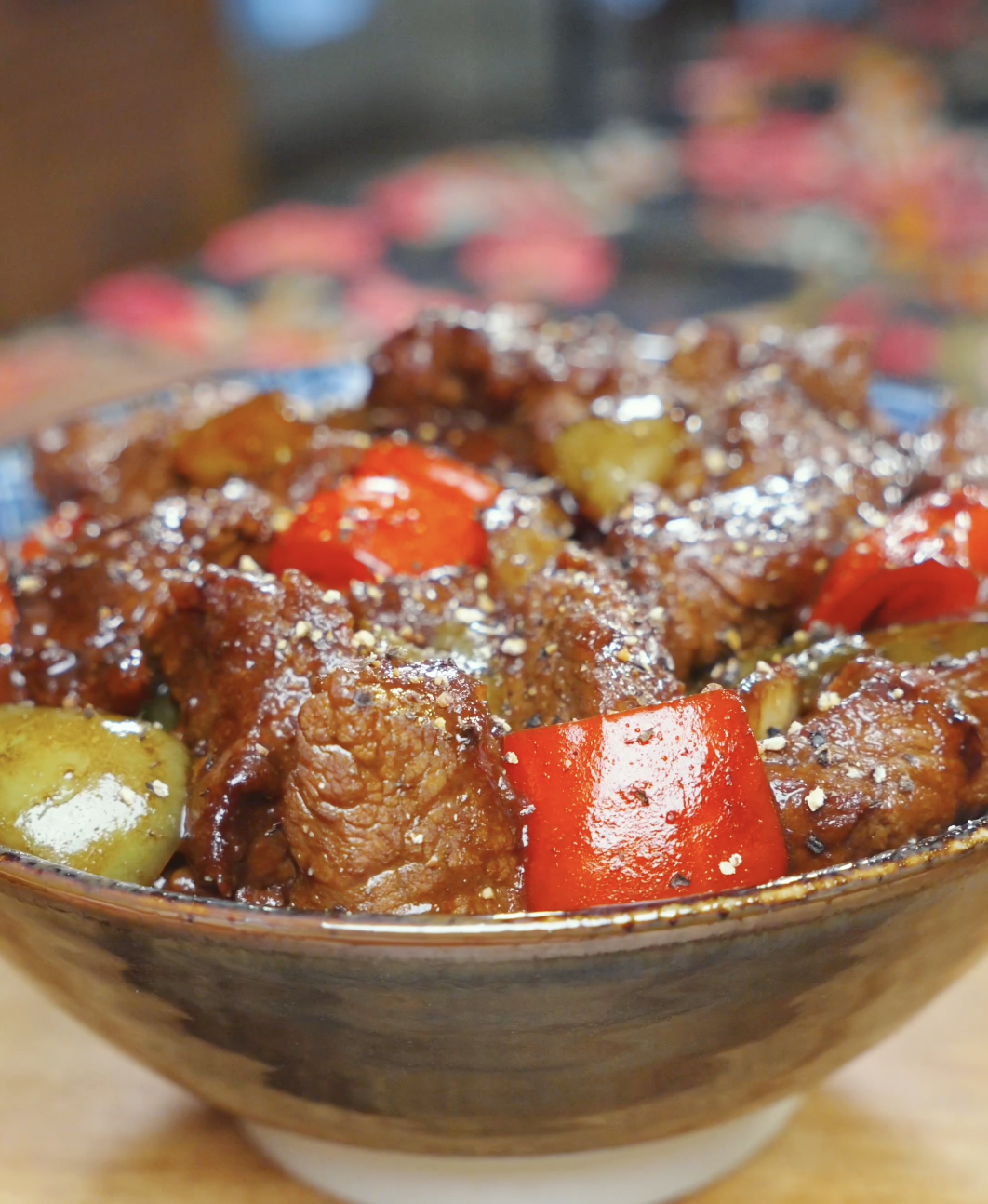 Finished Black Pepper Steak Bites Recipe in a ceramic bowl with red and green peppers and cracked black pepper.