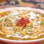 Finished Chicken Curry Stew Recipe in a pink bowl with cream, scallions, and dried peppers.