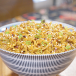 Finished Creamy Curry Noodles Recipe in a patterned bowl topped with sesame seeds, scallions, and red chili flakes.
