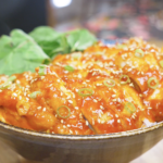 Finished Creamy Gochujang Chicken Recipe sliced over rice with sesame seeds, scallions, and greens.