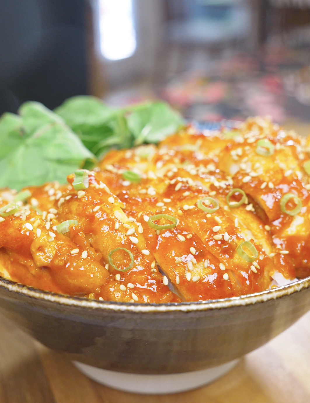 Finished Creamy Gochujang Chicken Recipe sliced over rice with sesame seeds, scallions, and greens.