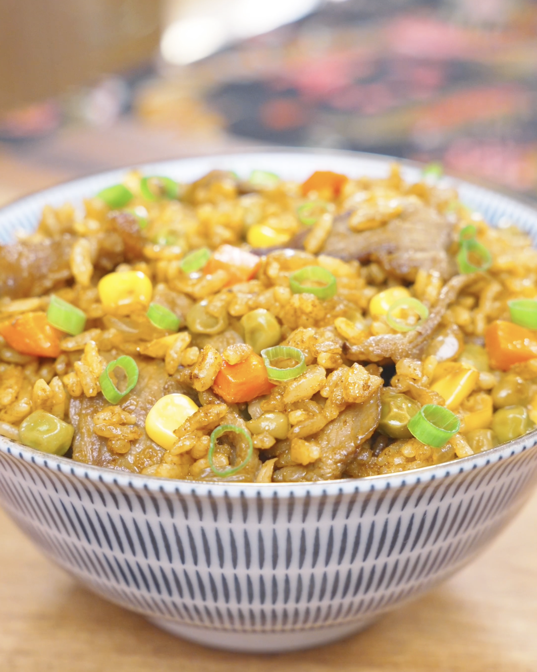 Finished Curry Fried Rice Recipe in a patterned bowl with beef, peas, corn, carrots, and scallions.