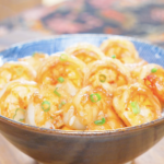 Finished Garlic Butter Shrimp Recipe in a blue bowl over rice with garlic and scallions.