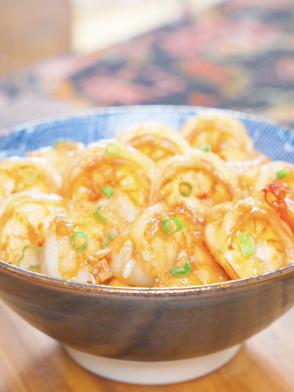 Finished Garlic Butter Shrimp Recipe in a blue bowl over rice with garlic and scallions.