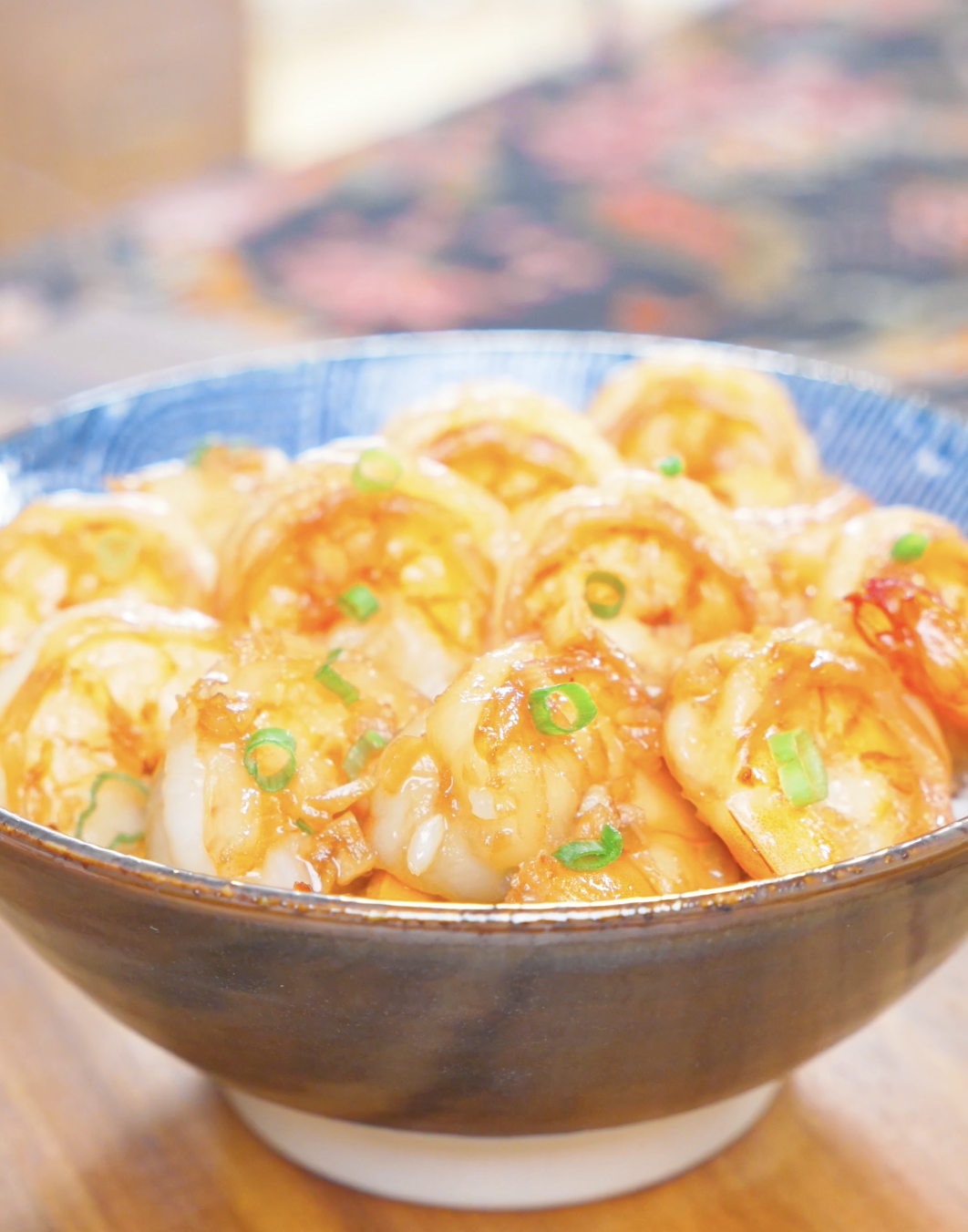 Finished Garlic Butter Shrimp Recipe in a blue bowl over rice with garlic and scallions.