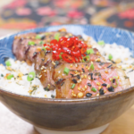 Finished Japanese Steak Bowl Recipe with garlic-glazed sliced steak over rice, furikake, scallions, and red peppers.
