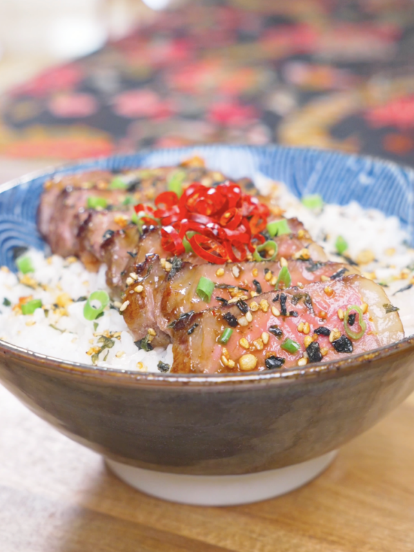 Finished Japanese Steak Bowl Recipe with garlic-glazed sliced steak over rice, furikake, scallions, and red peppers.
