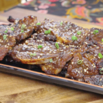 Finished Korean BBQ Short Rib Recipe on a platter with charred edges, sesame seeds, and scallions.