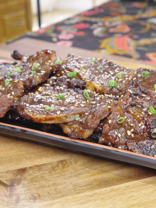 Finished Korean BBQ Short Rib Recipe on a platter with charred edges, sesame seeds, and scallions.