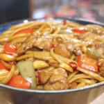 Finished Kung Pao Chicken Noodles Recipe in a bowl with chicken, bell peppers, and dried chilies.