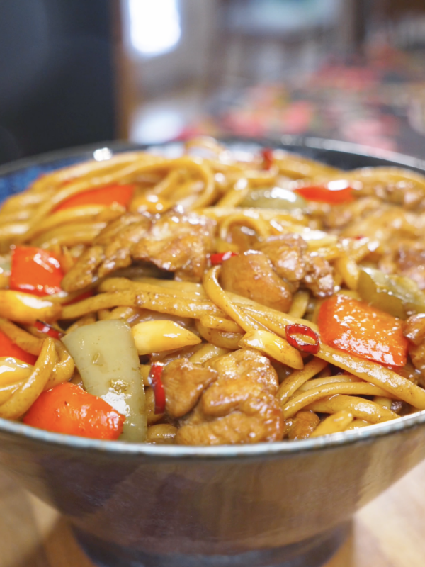 Finished Kung Pao Chicken Noodles Recipe in a bowl with chicken, bell peppers, and dried chilies.