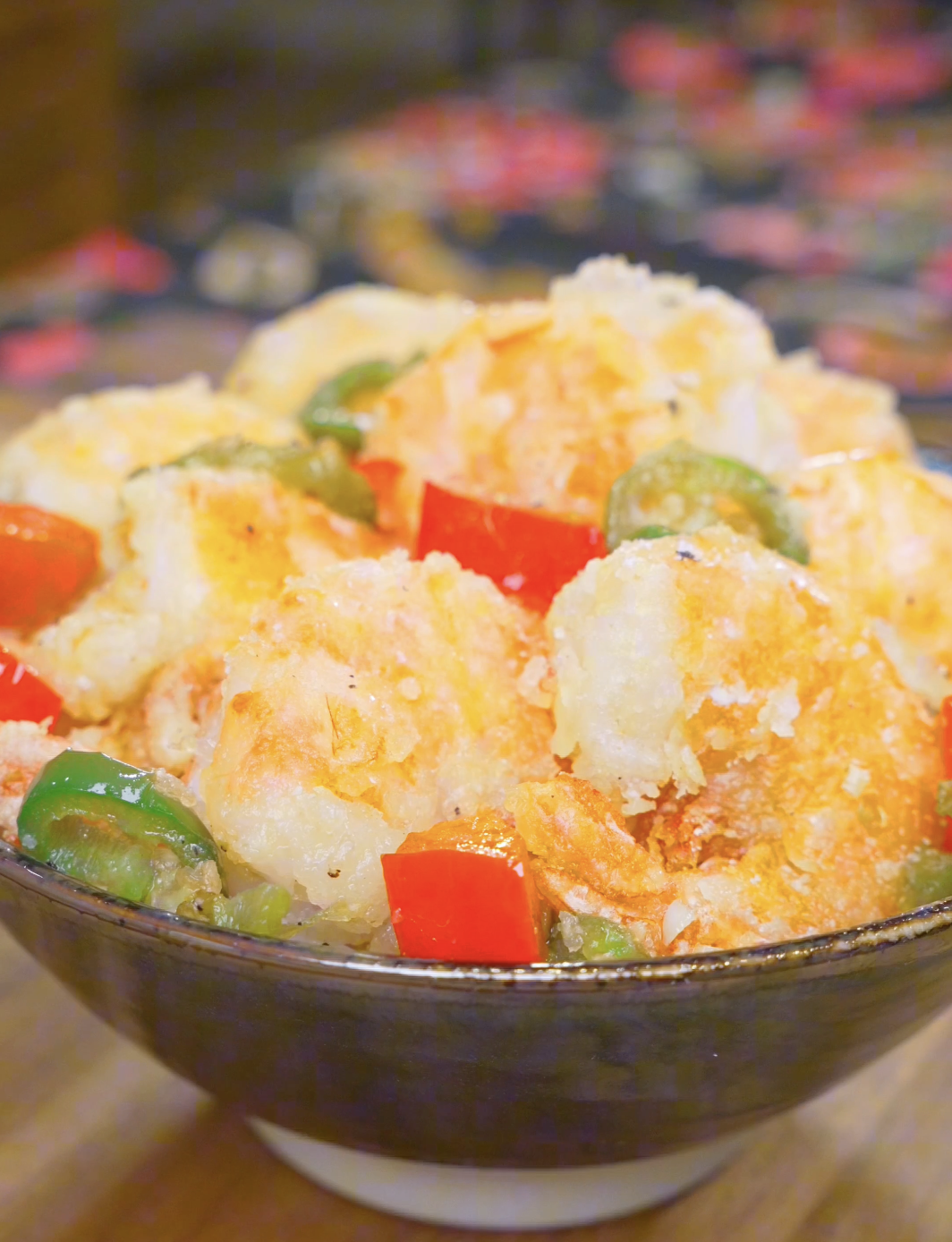 Finished Salt and Pepper Shrimp Recipe in a dark bowl with crispy shell-on shrimp, red bell pepper, and jalape&ntilde;o.