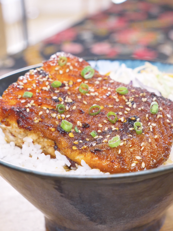Finished Spicy Salmon Bowl Recipe with chili crunch glazed salmon over rice, sesame seeds, scallions, and coleslaw mix.