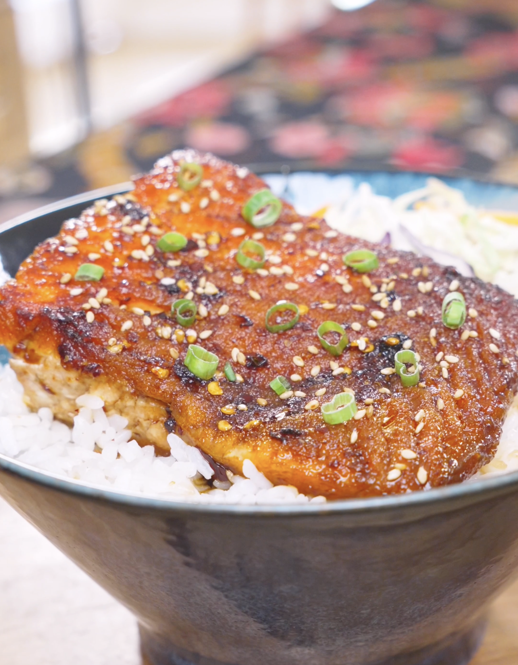 Finished Spicy Salmon Bowl Recipe with chili crunch glazed salmon over rice, sesame seeds, scallions, and coleslaw mix.