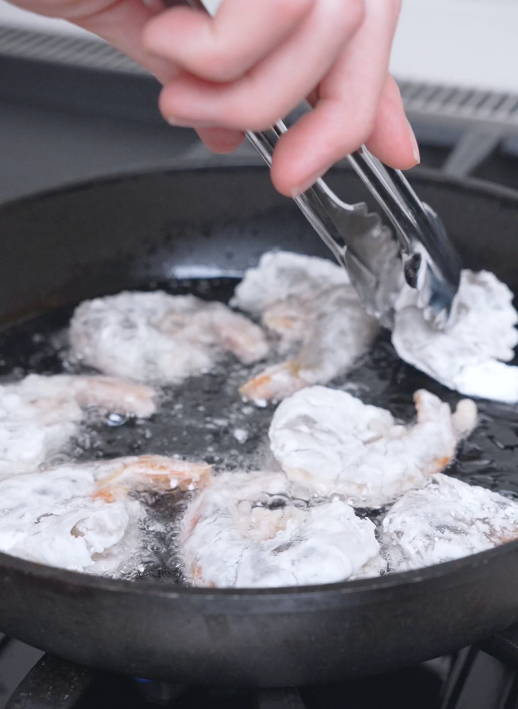 Cornstarch-coated shrimp shallow frying in bubbling oil for Salt and Pepper Shrimp Recipe.
