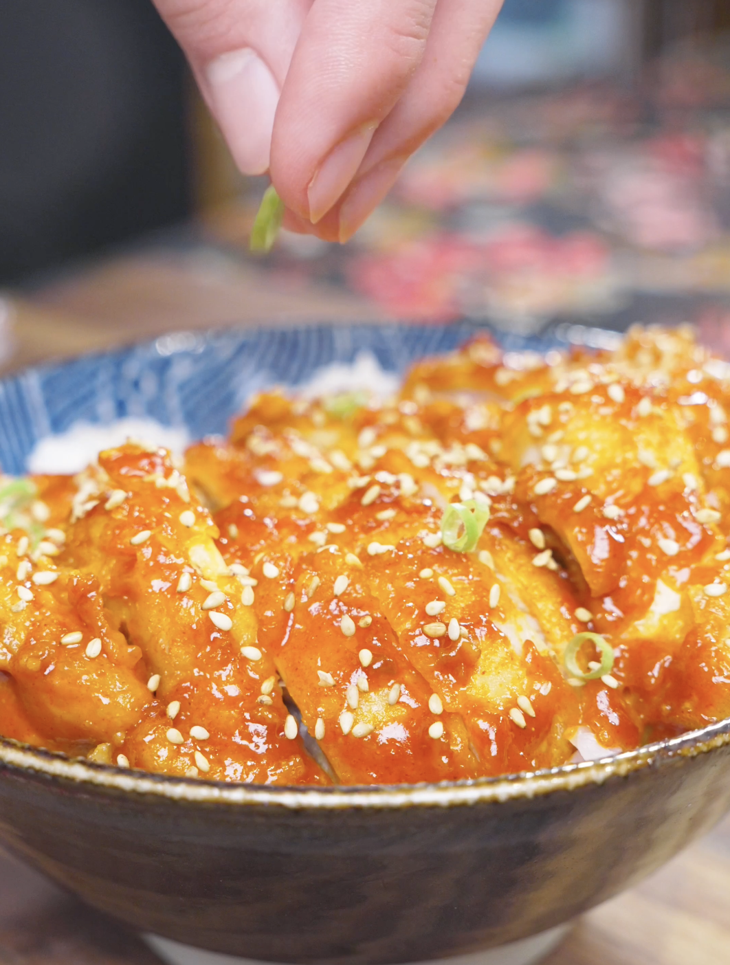 Sliced scallions being sprinkled over sesame-topped sliced chicken for Creamy Gochujang Chicken Recipe.