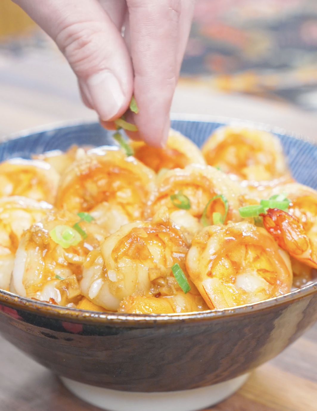 Sliced scallions being sprinkled over the glossy shrimp for Garlic Butter Shrimp Recipe.