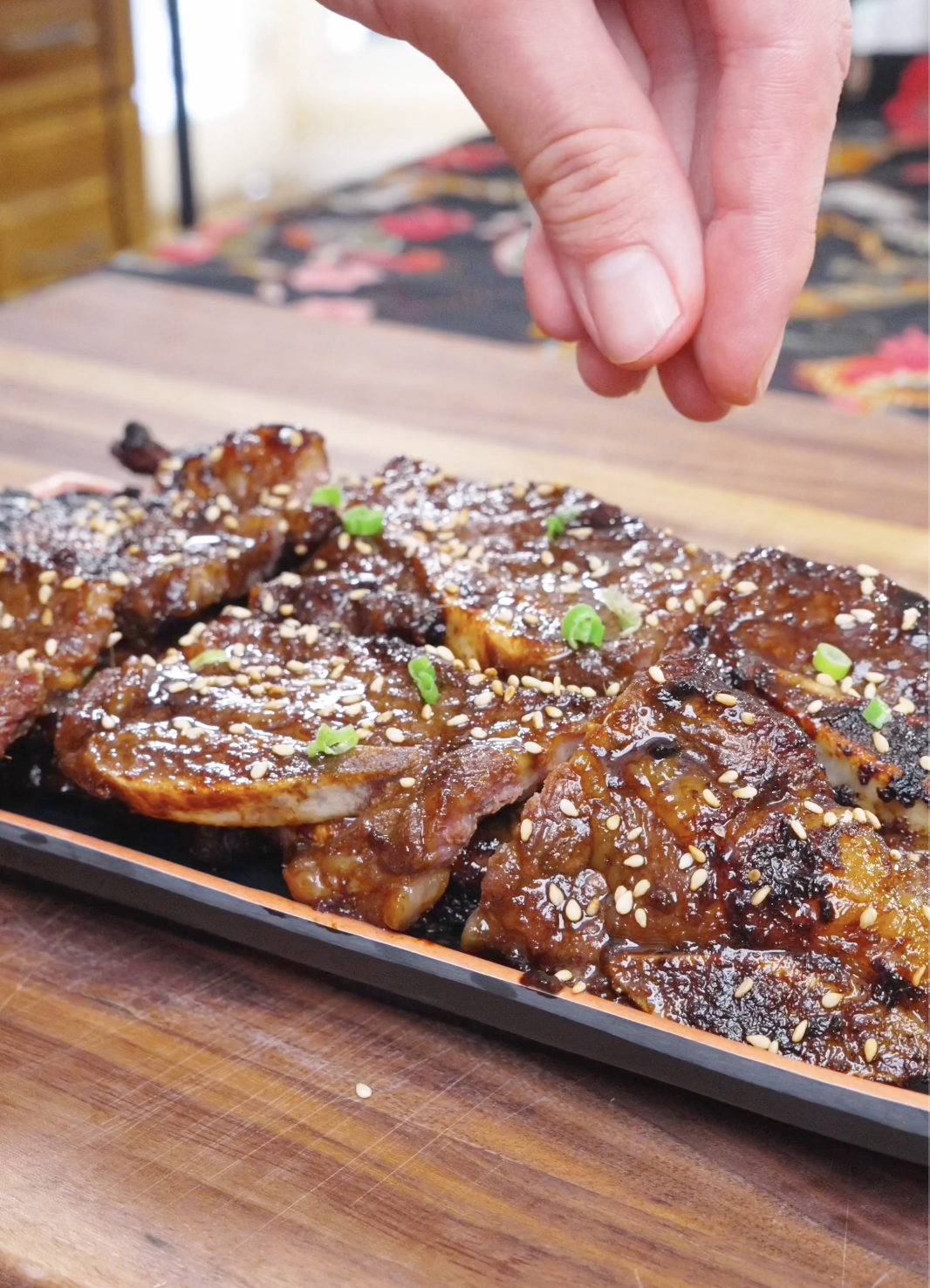 Sesame seeds being sprinkled over the grilled short ribs and scallions for Korean BBQ Short Rib Recipe.