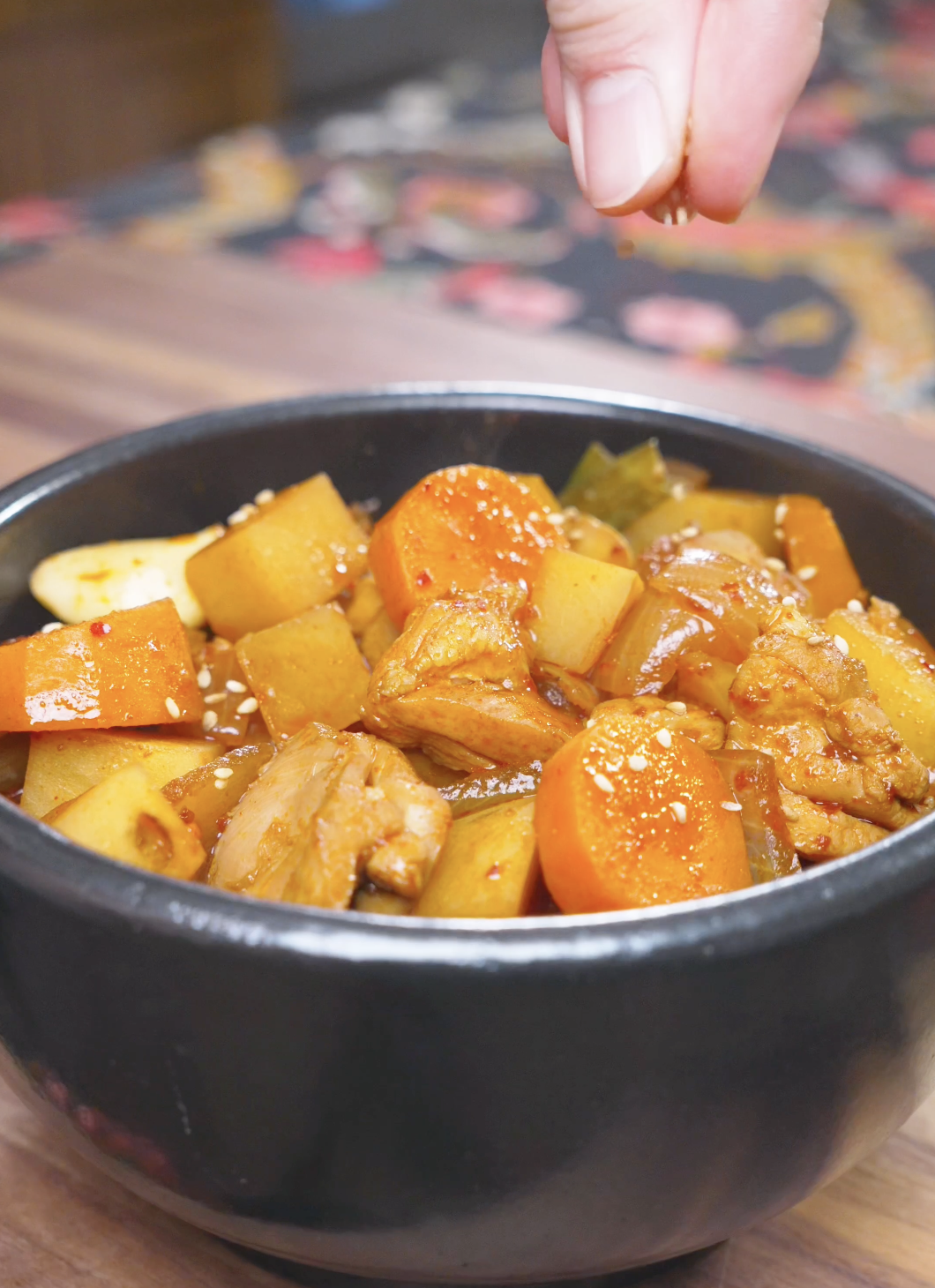 Sesame seeds being sprinkled over a finished bowl of Korean Braised Chicken Recipe.