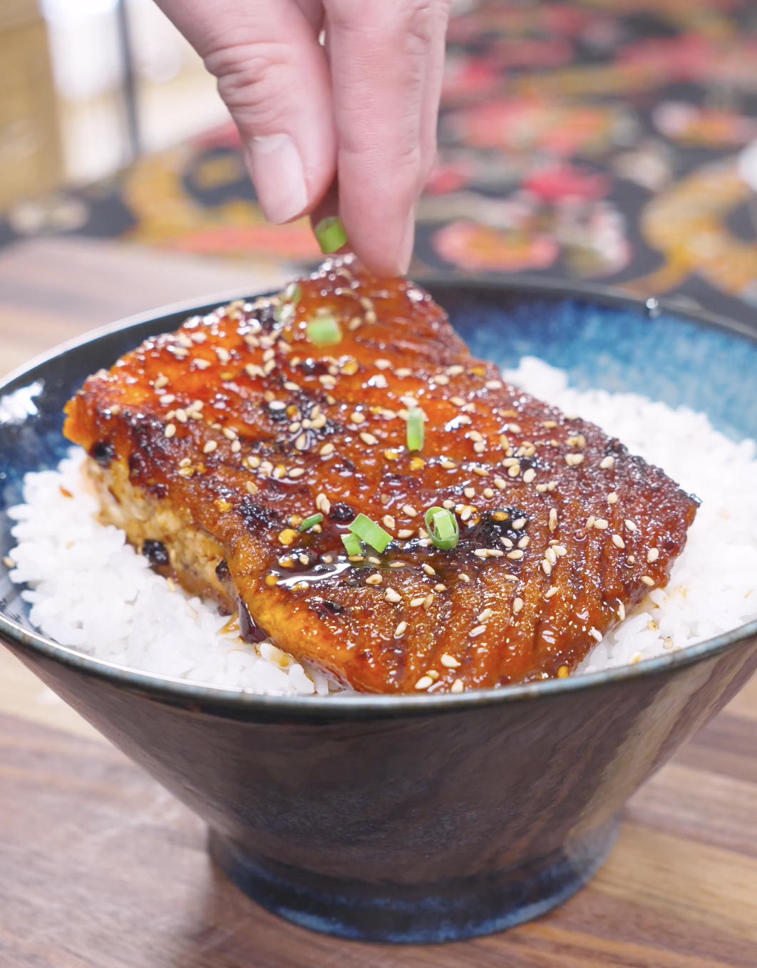 Sliced scallions being sprinkled over sesame-topped glazed salmon for Spicy Salmon Bowl Recipe.