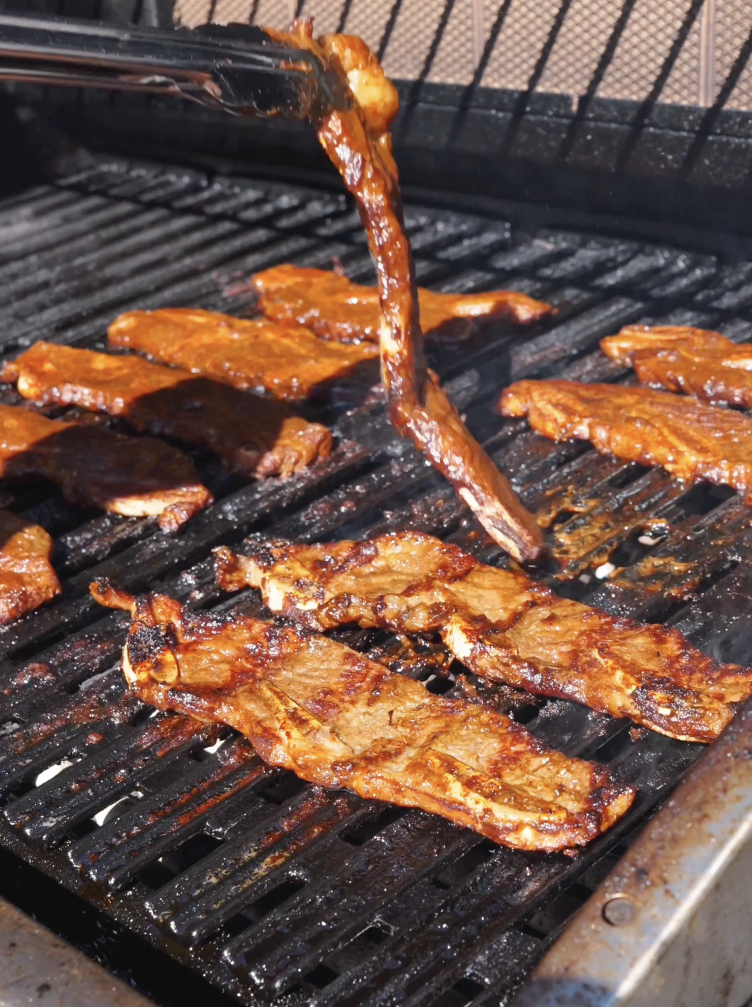Marinated short ribs laid across a hot grill grate for Korean BBQ Short Rib Recipe.