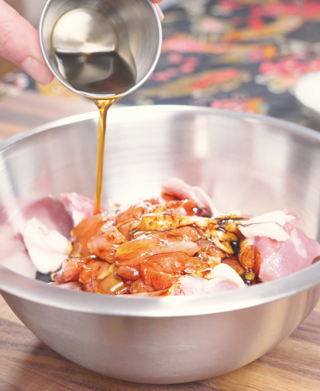 Soy sauce marinade being poured over cubed chicken thighs with garlic and ginger for Garlic Teriyaki Chicken Recipe.