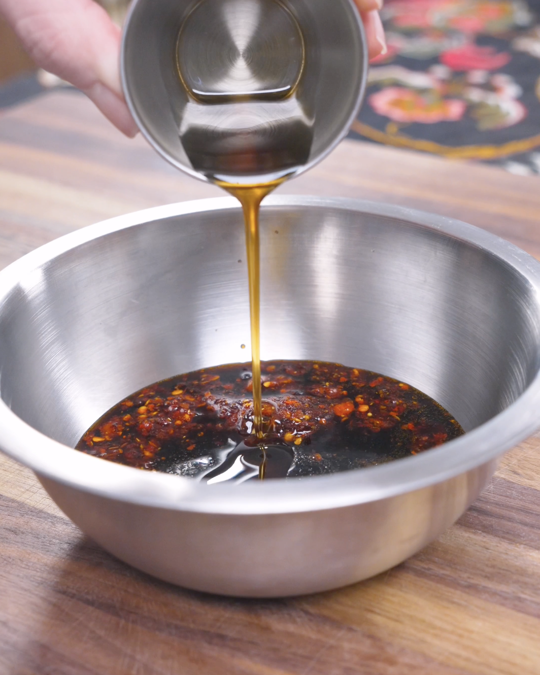 Sesame oil being poured into chili crunch, soy sauce, rice vinegar, and honey for Spicy Salmon Bowl Recipe.