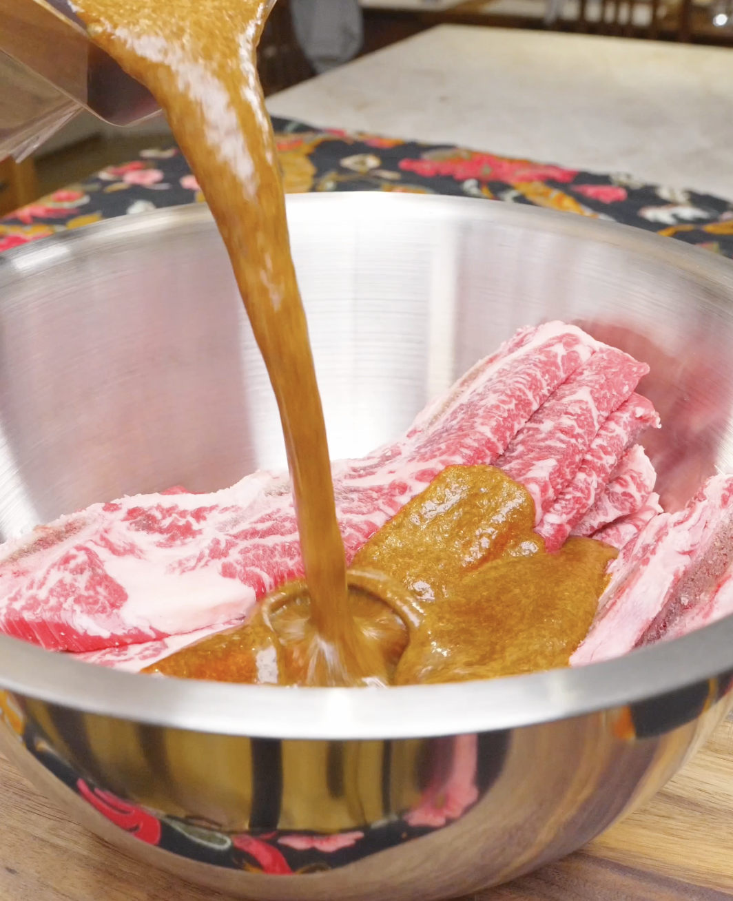 Blended pear marinade being poured over thinly sliced raw short ribs for Korean BBQ Short Rib Recipe.
