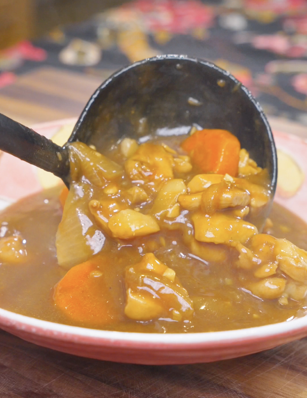 A ladle spooning chicken, potatoes, and carrots into a shallow bowl for Chicken Curry Stew Recipe.