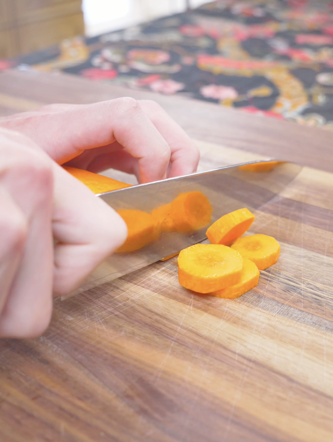 A carrot being cut into thick rounds on a wooden board while prepping Korean Braised Chicken Recipe.