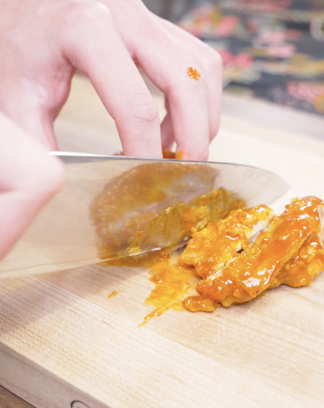 Glazed chicken being sliced on a wooden board for Creamy Gochujang Chicken Recipe.