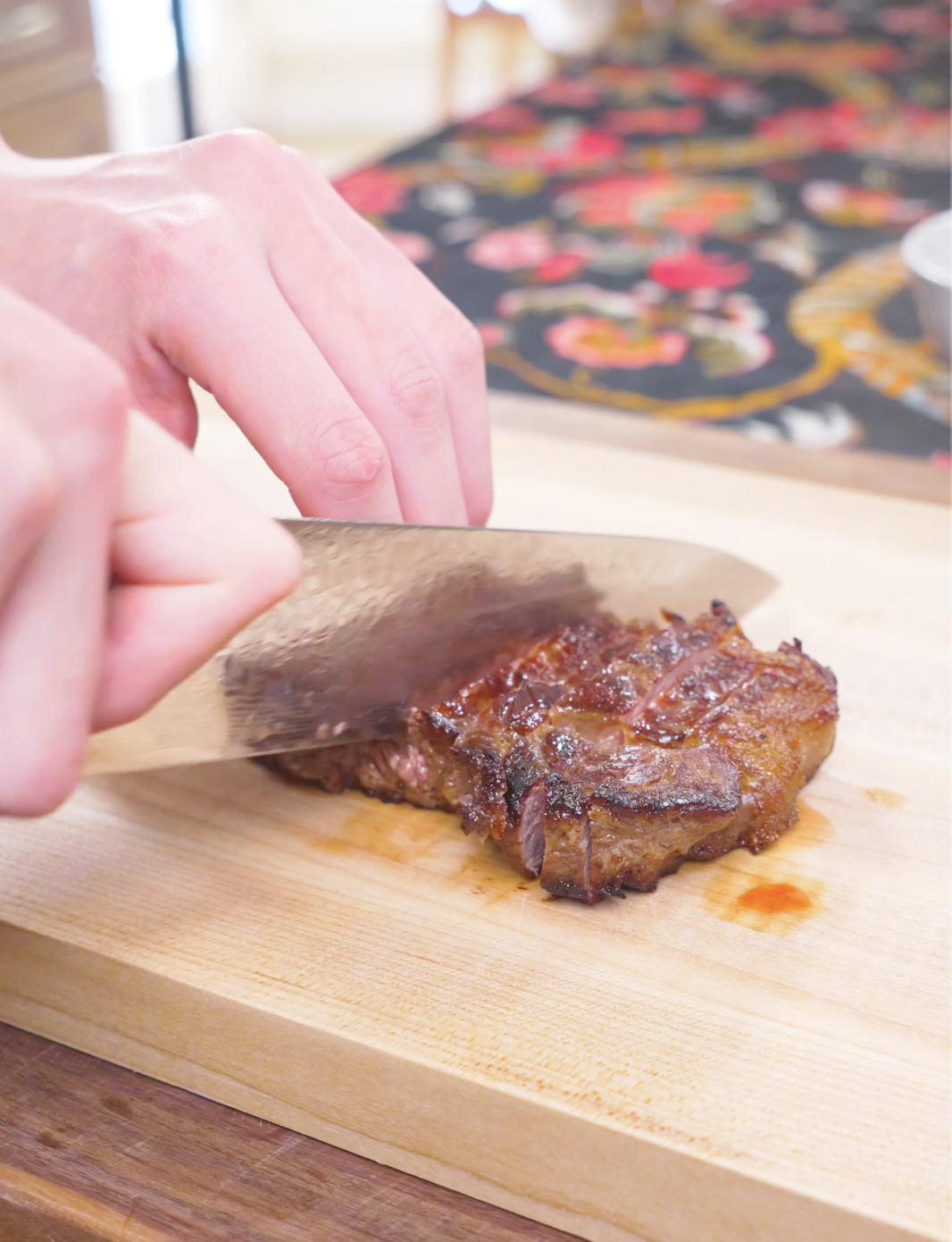 Rested steak being sliced thin with a knife on a wooden board for Japanese Steak Bowl Recipe.