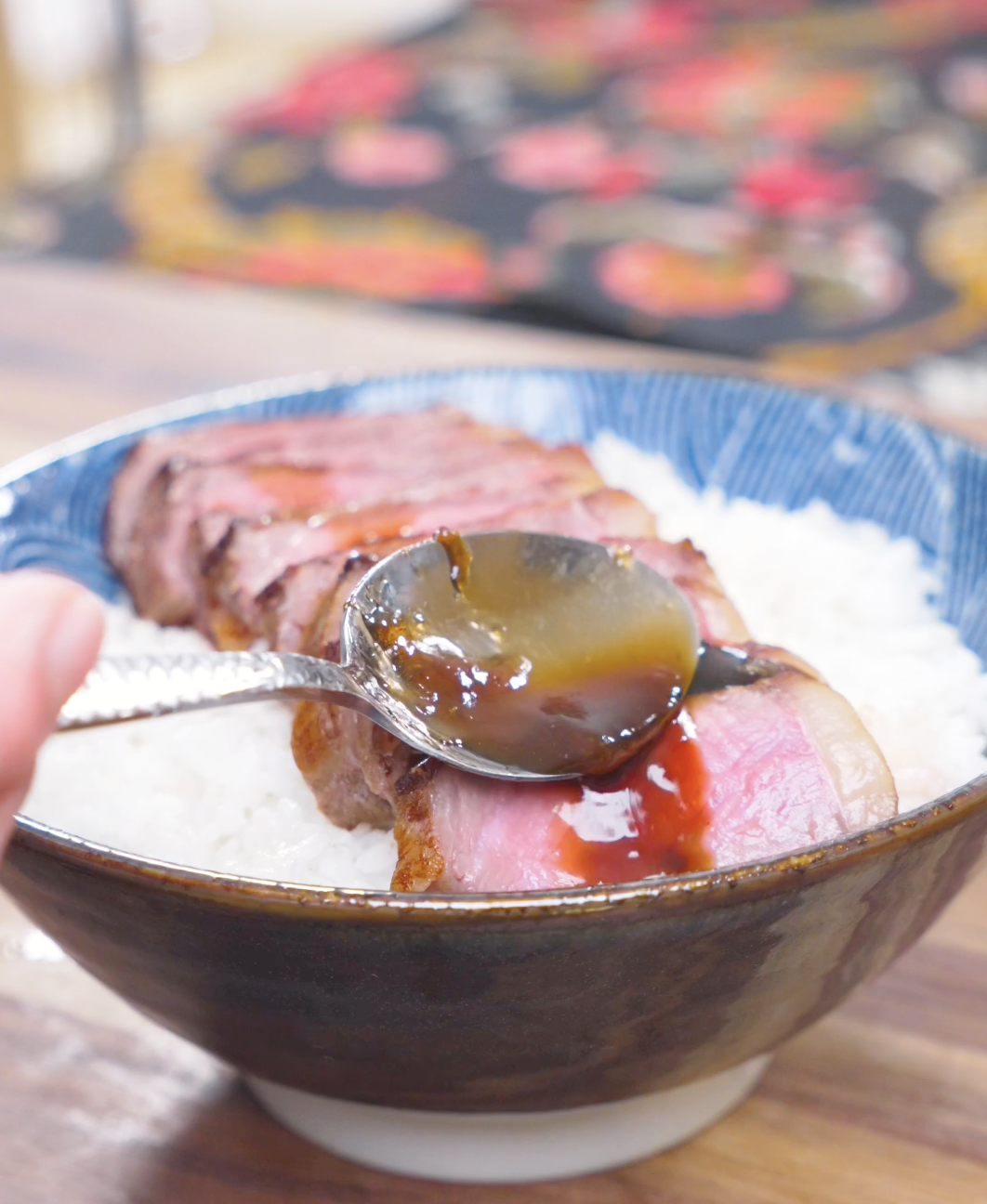 Glossy garlic sauce being spooned over sliced steak and rice for Japanese Steak Bowl Recipe.