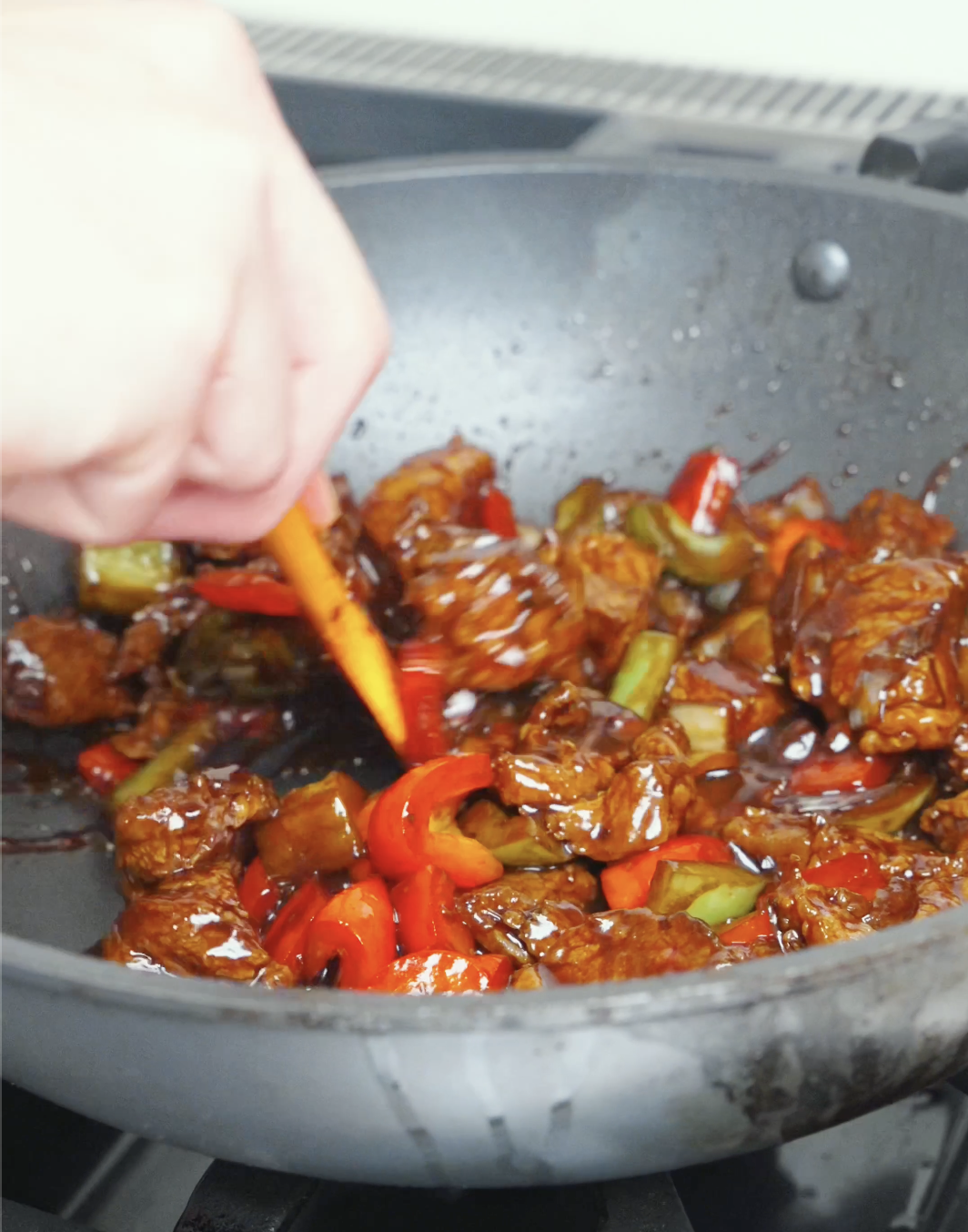 Steak and bell peppers being tossed in a thick, glossy sauce while finishing Black Pepper Steak Bites Recipe.