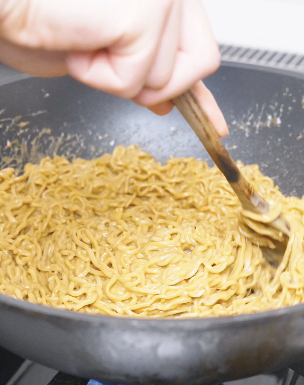 Noodles and reserved noodle water being tossed until the sauce clings for Creamy Curry Noodles Recipe.