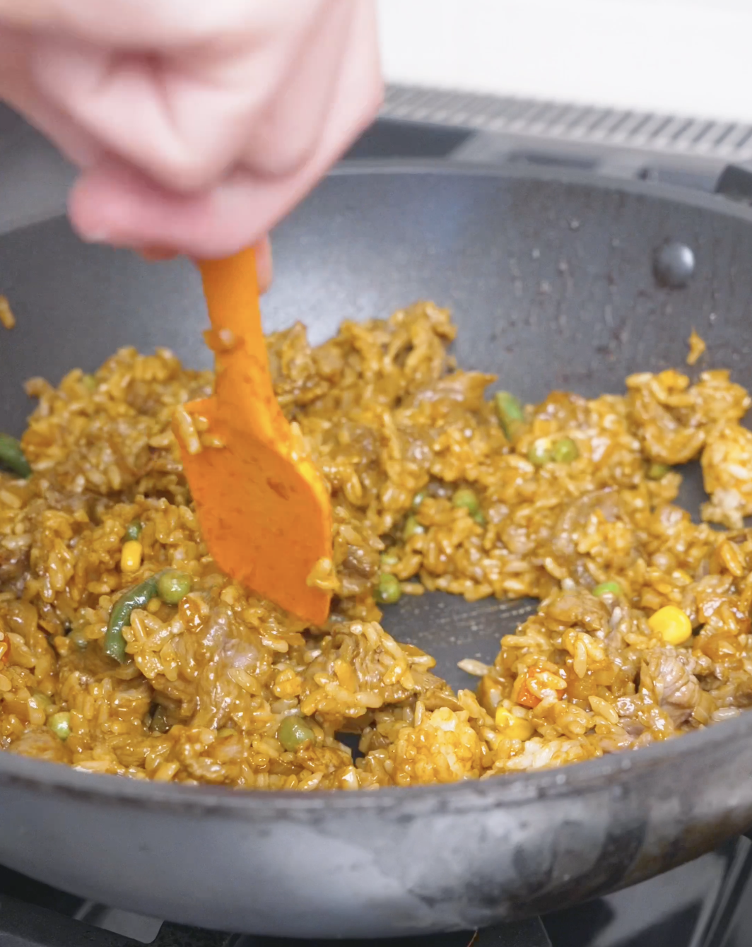 Rice, beef, and vegetables being tossed until every grain is evenly coated for Curry Fried Rice Recipe.