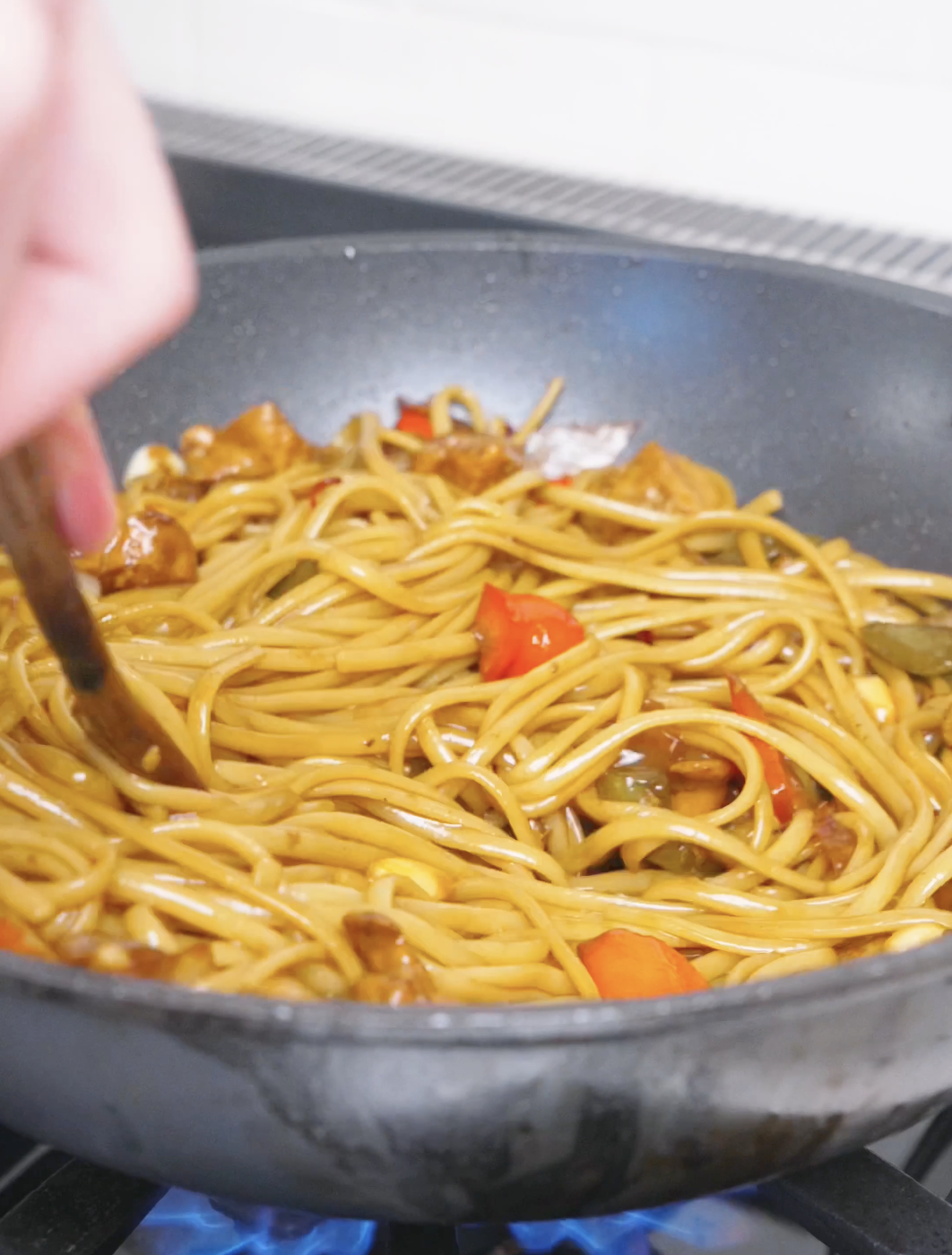 Noodles being tossed until every strand is coated in the glossy sauce for Kung Pao Chicken Noodles Recipe.